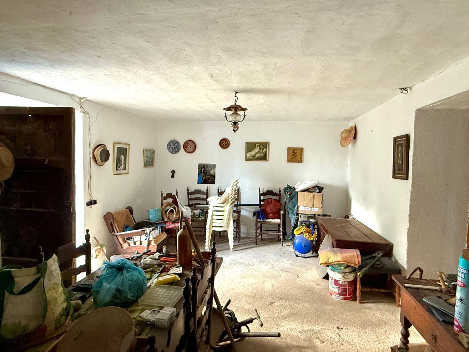 A panoramic view of a dimly lit basement room with white walls, furniture, and various decorative items on display.
