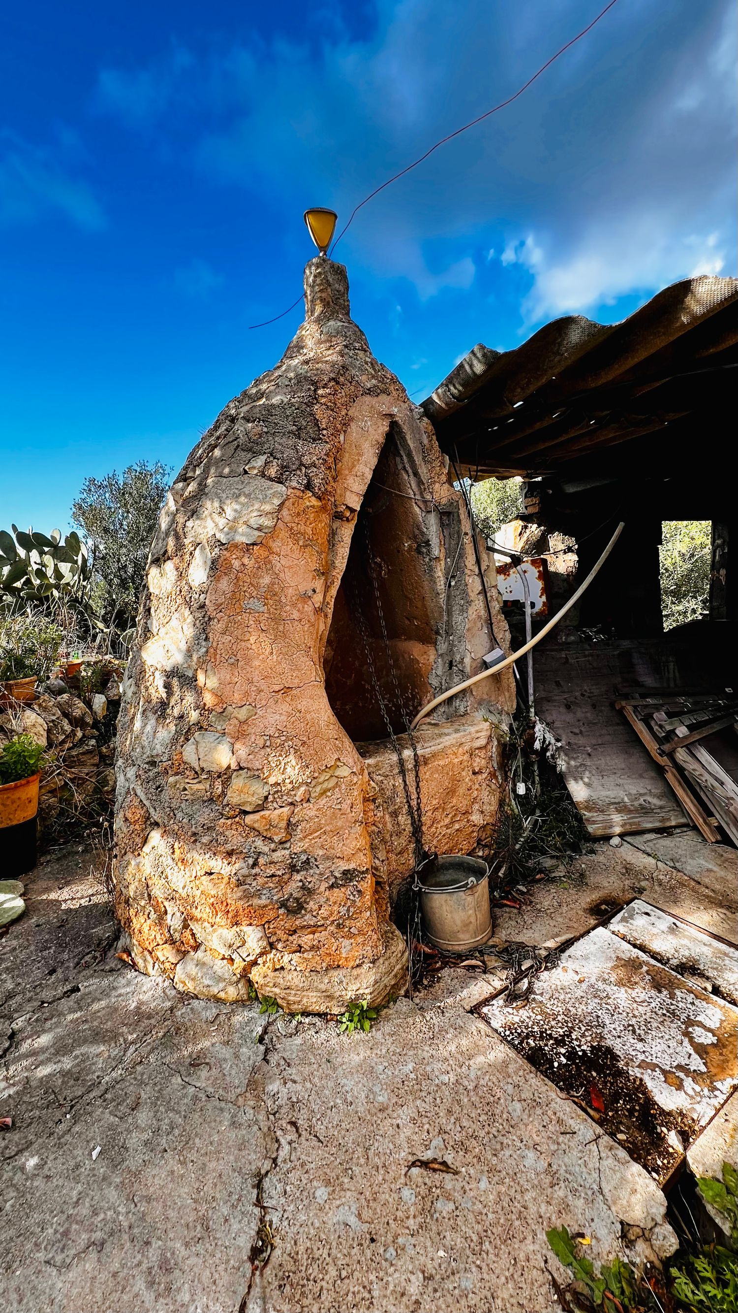 A series of old stone ovens or kilns with deteriorating brick walls set against a bright blue sky.