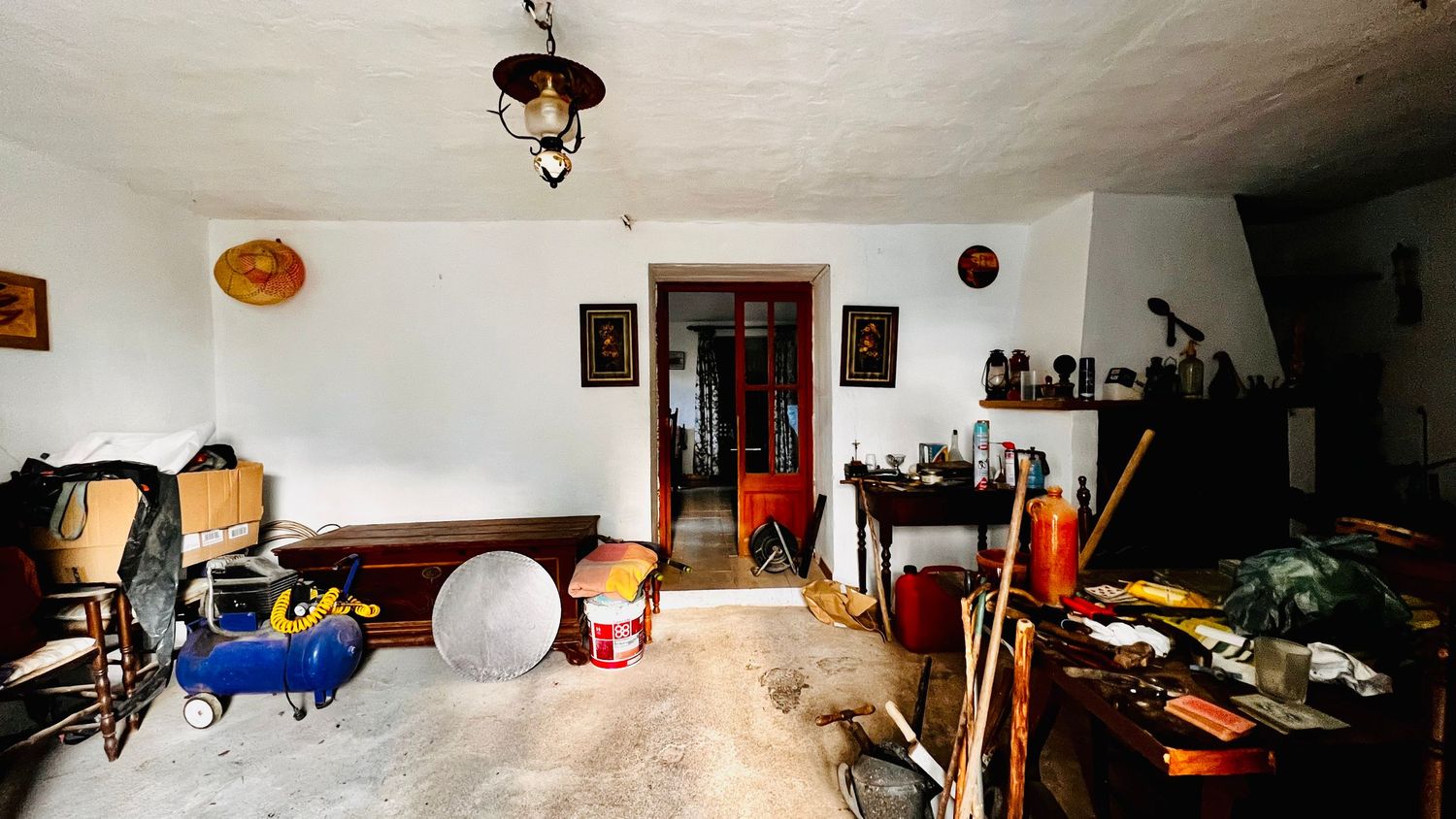 A panoramic view of a cluttered garage interior with storage shelves, tools, and miscellaneous household items.
