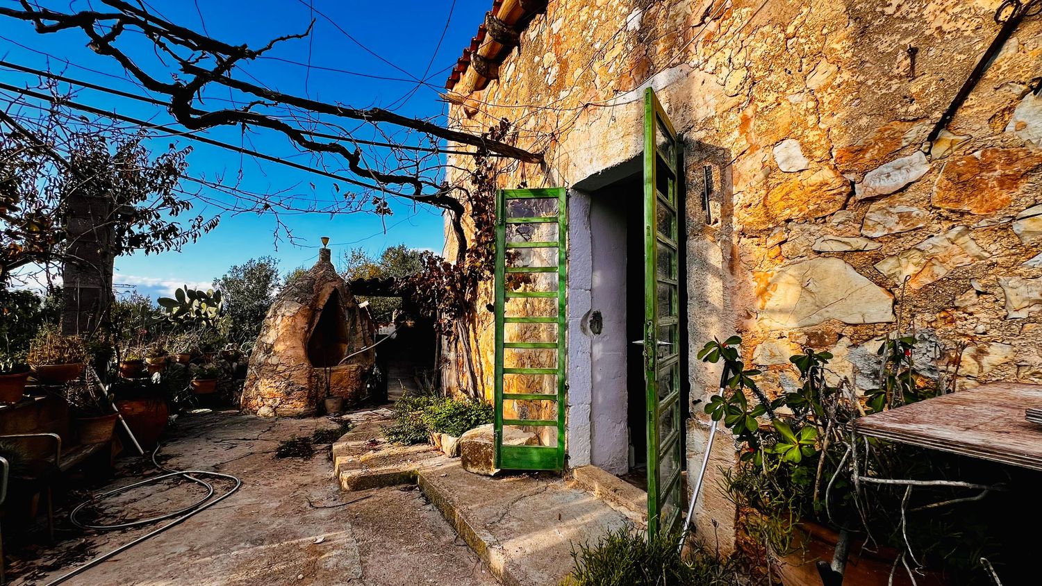 Ancient stone walls and rustic archways create a charming pathway through a historic Mediterranean village in golden sunlight.