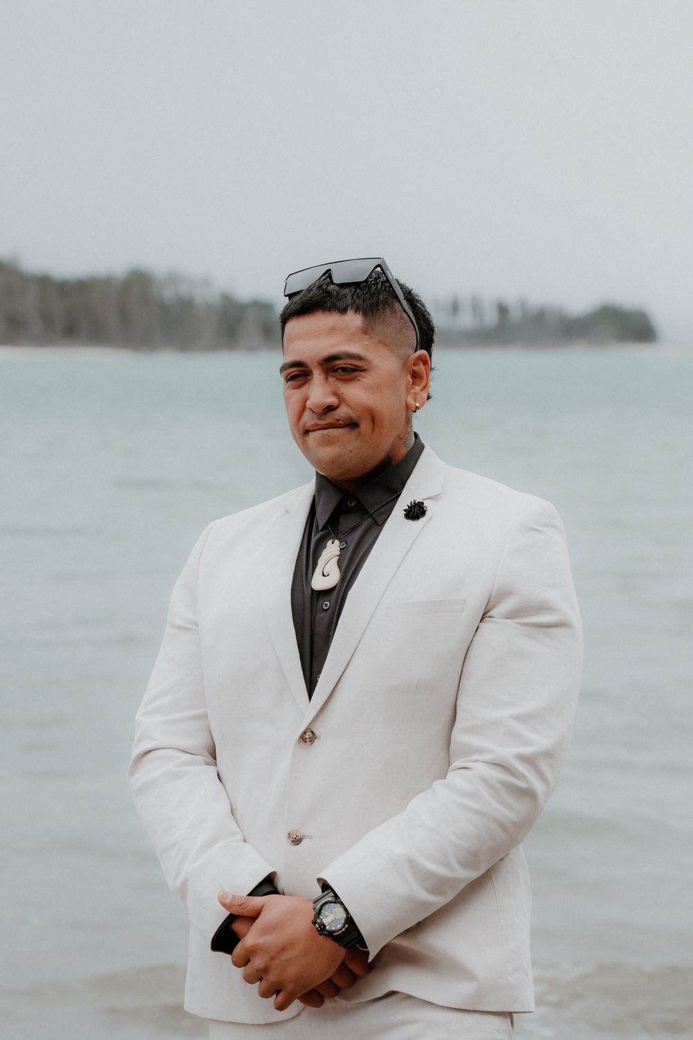 Person in crisp white blazer smiles against cloudy oceanfront backdrop.