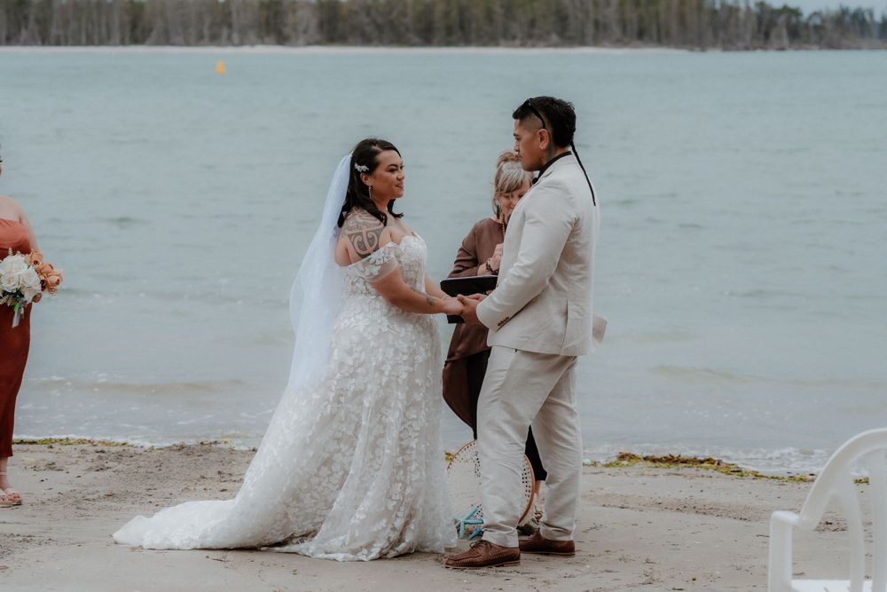 Intimate beach wedding ceremony with couple exchanging vows by the water.