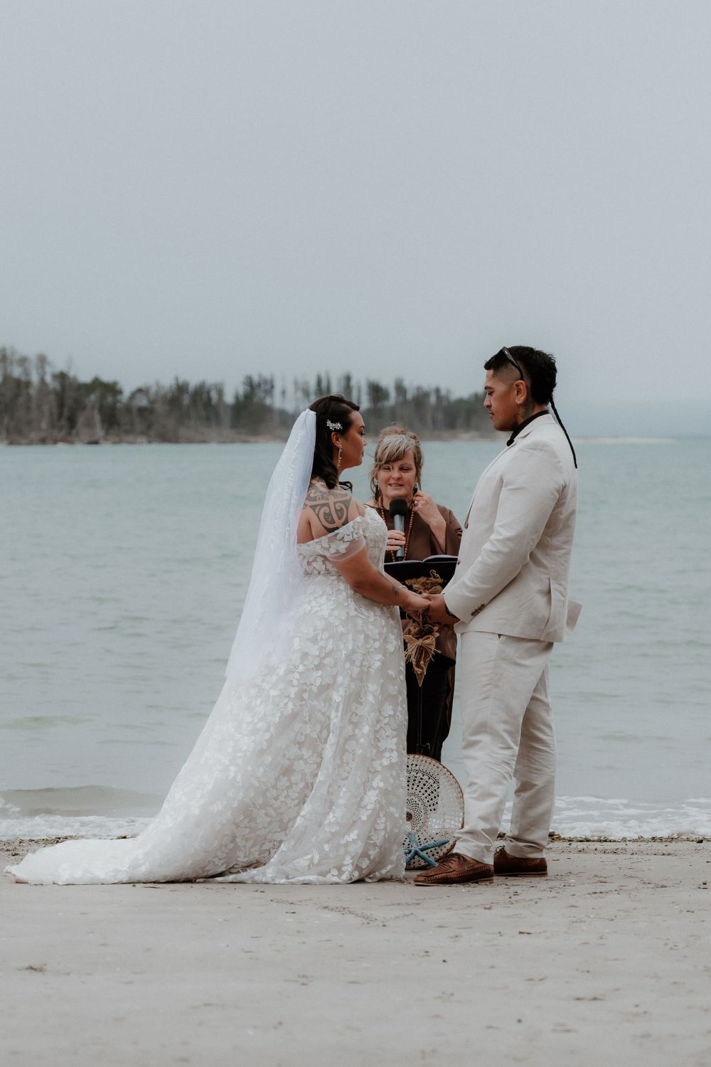 A beachside wedding ceremony with an officiant leading the service against a coastal backdrop.