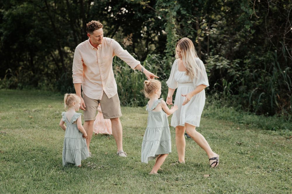 A joyful family moment captured while playing together in a sunlit green field.