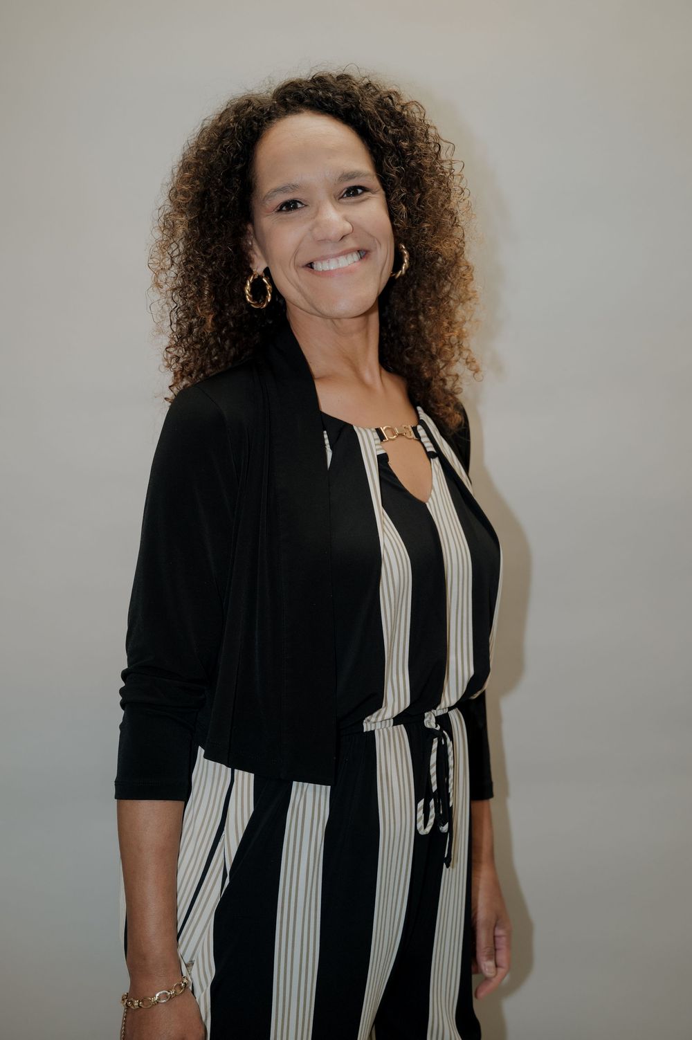 Professional woman in black cardigan and striped dress smiling at camera.