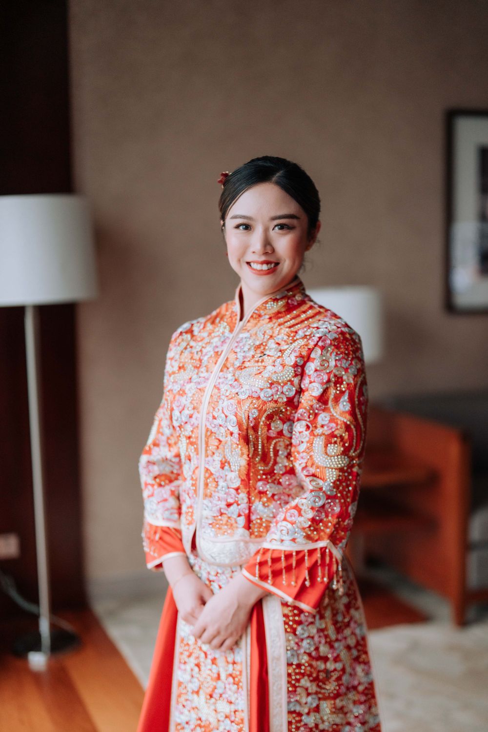 Someone wearing a traditional red and white Chinese qipao dress poses in an elegant room setting.