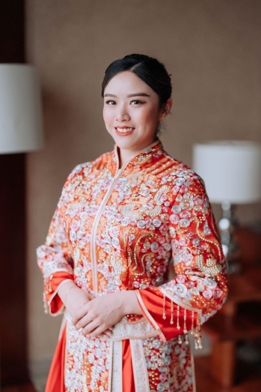 Portrait of someone wearing an intricately embroidered orange and white Chinese traditional dress.