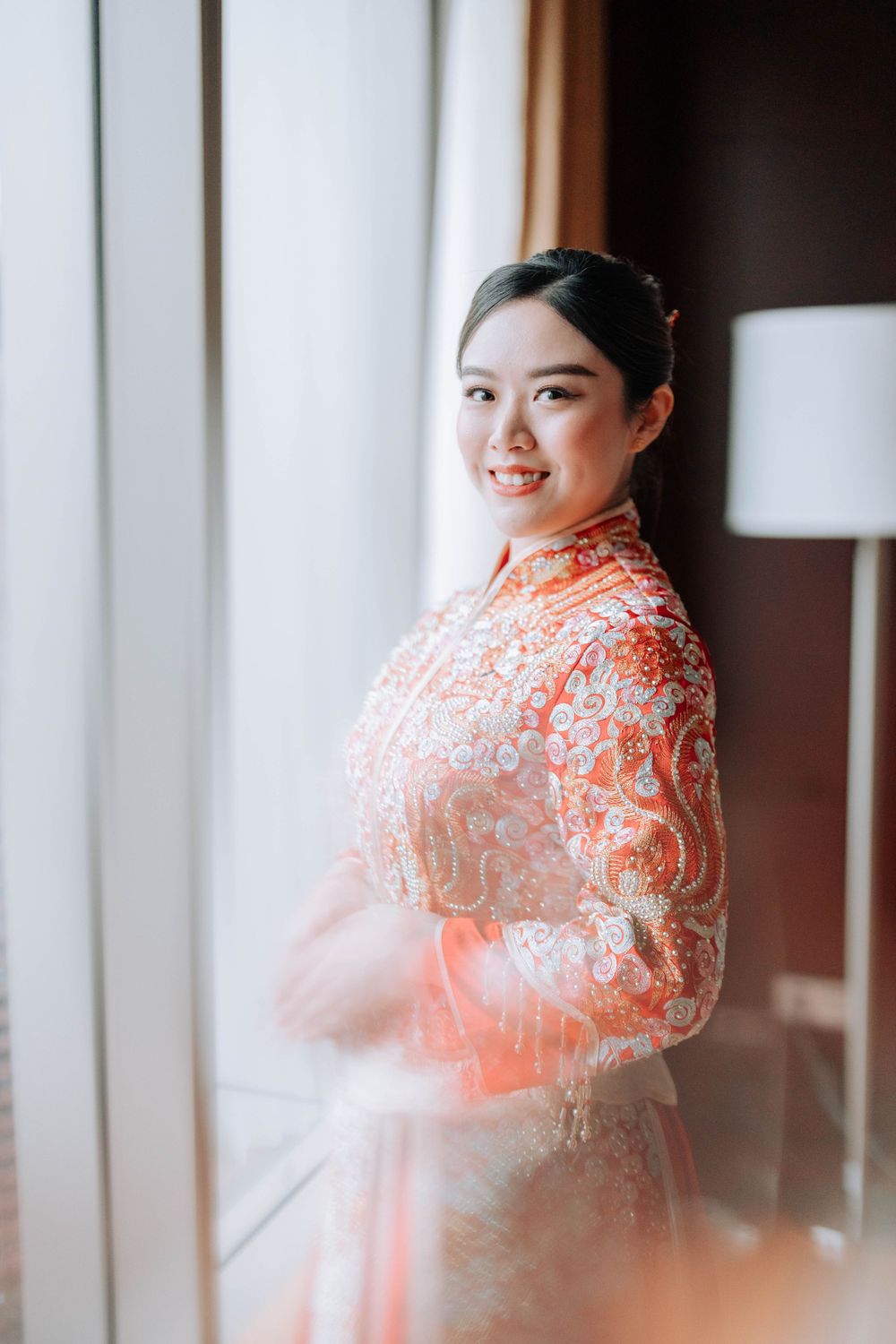 A person in a traditional Chinese dress stands by a window in soft natural light.