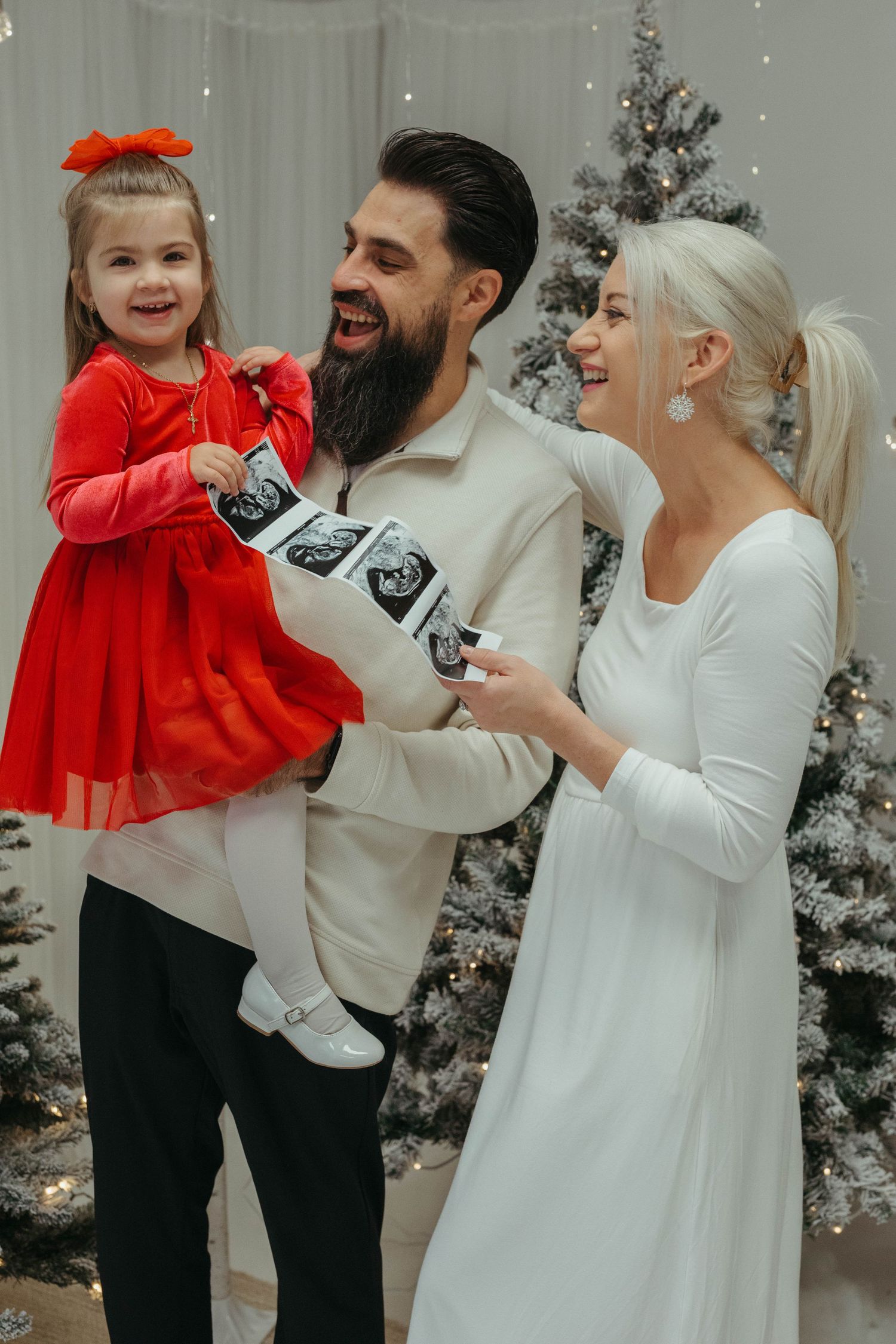 Family shares joyful moment opening Christmas presents in front of decorated tree.