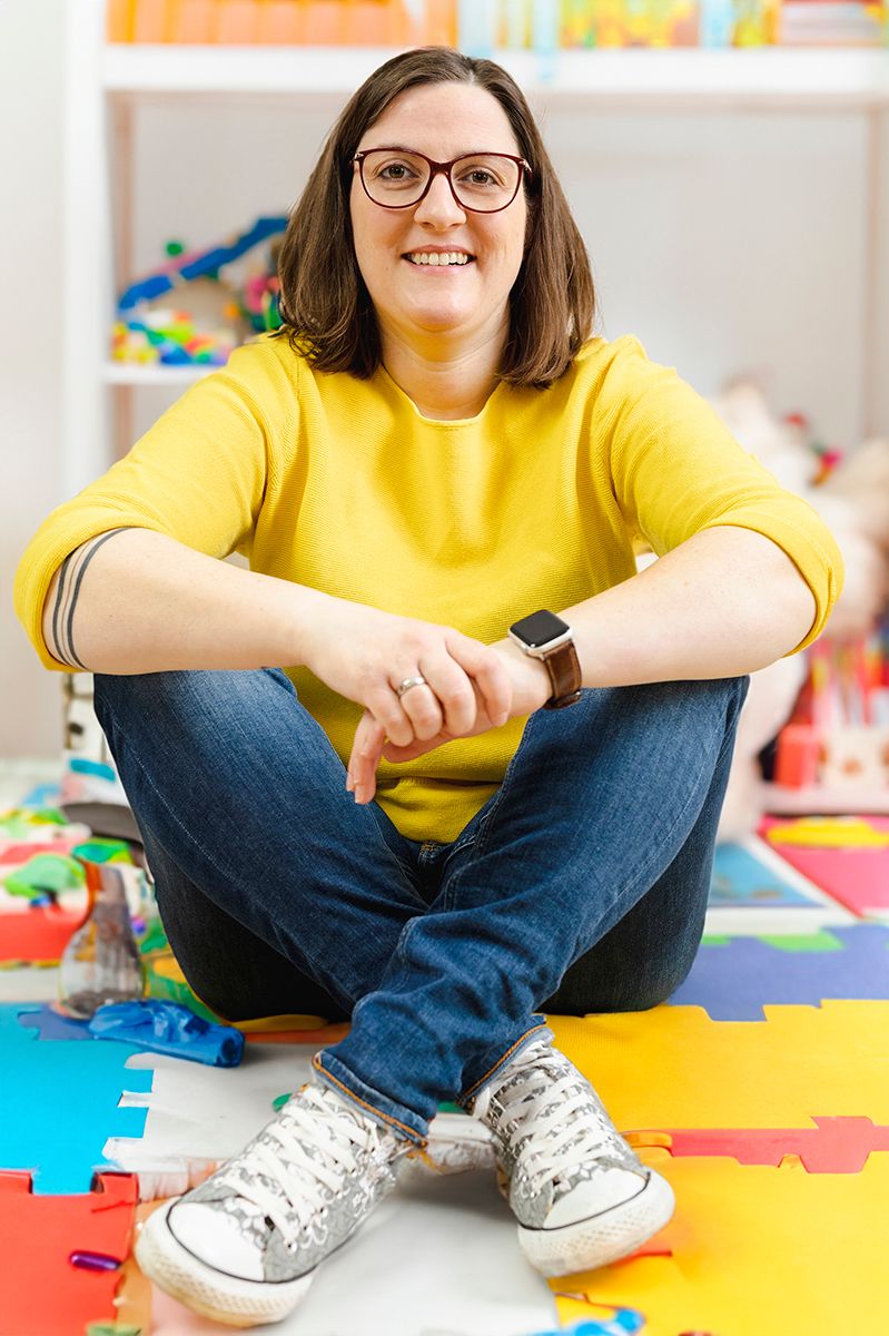 Bewerbungsfoto einer Erzieherin auf dem Boden sitzend im Schneidersitz im Studio in Bad Arolsen