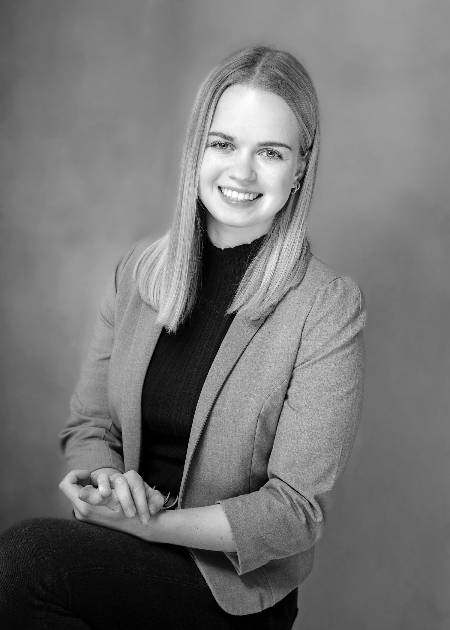 Headshot einer jungen selbstbewussten Frau sitzend in klassischem schwarz/ weiß und klassischer Kleidung