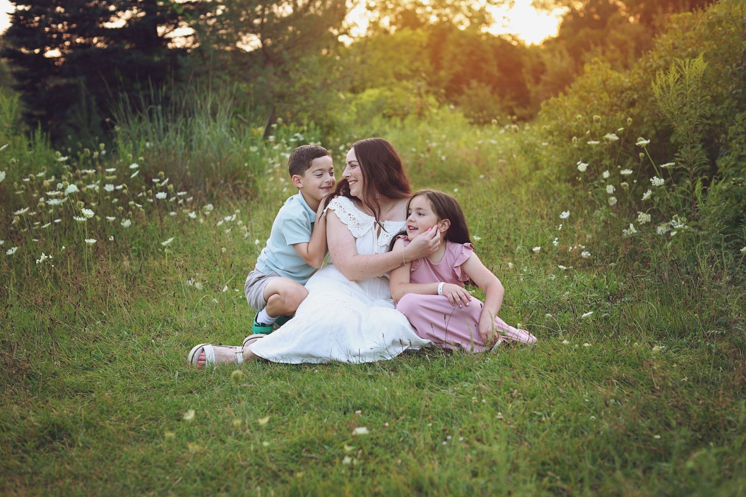 Family sitting together in a wildflower meadow at sunset.