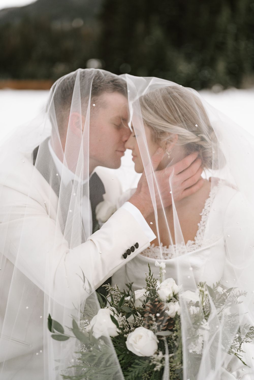 Romantic winter wedding portraits with veils and white florals in the snow.