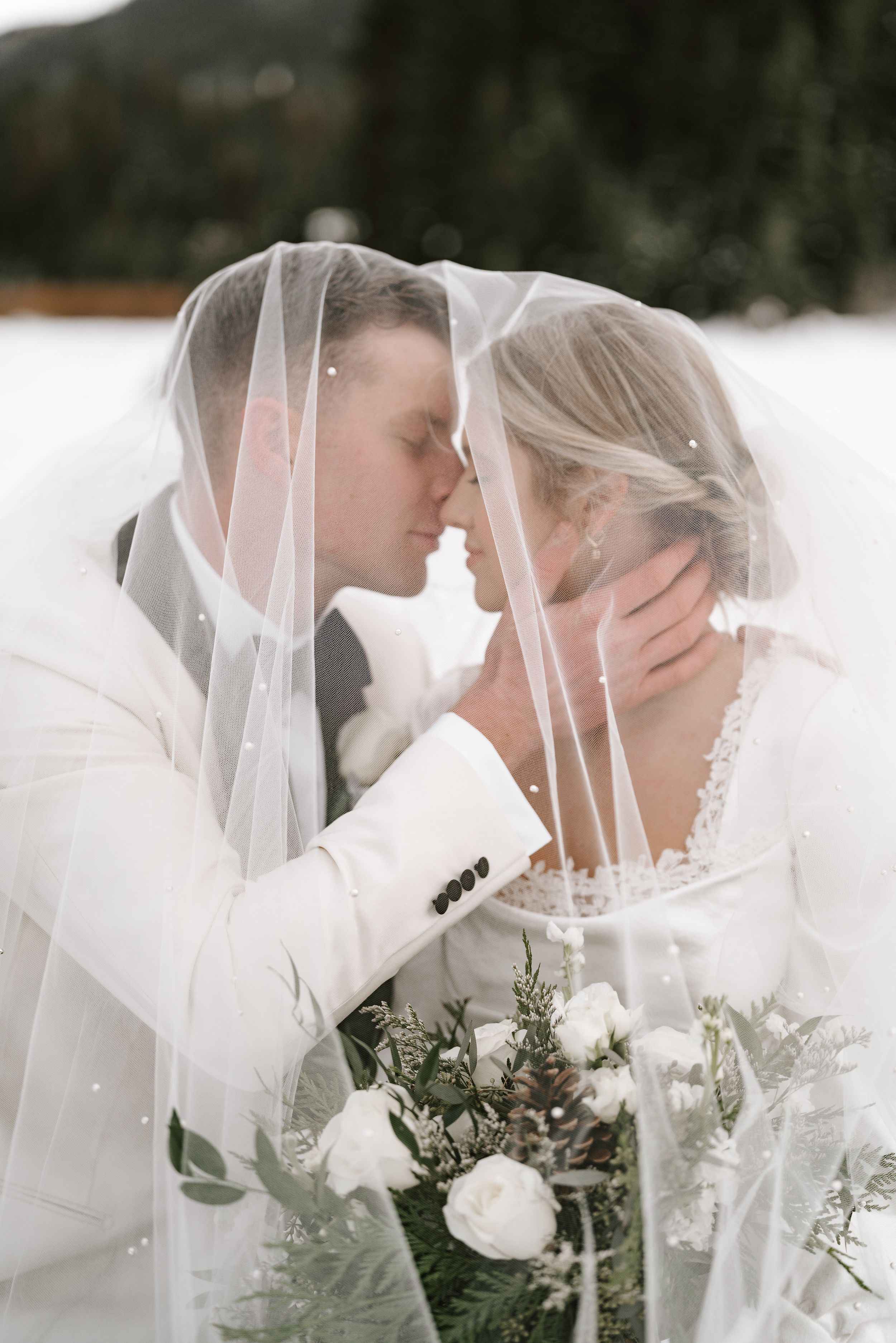 Romantic winter wedding portraits with veils and white florals in the snow.