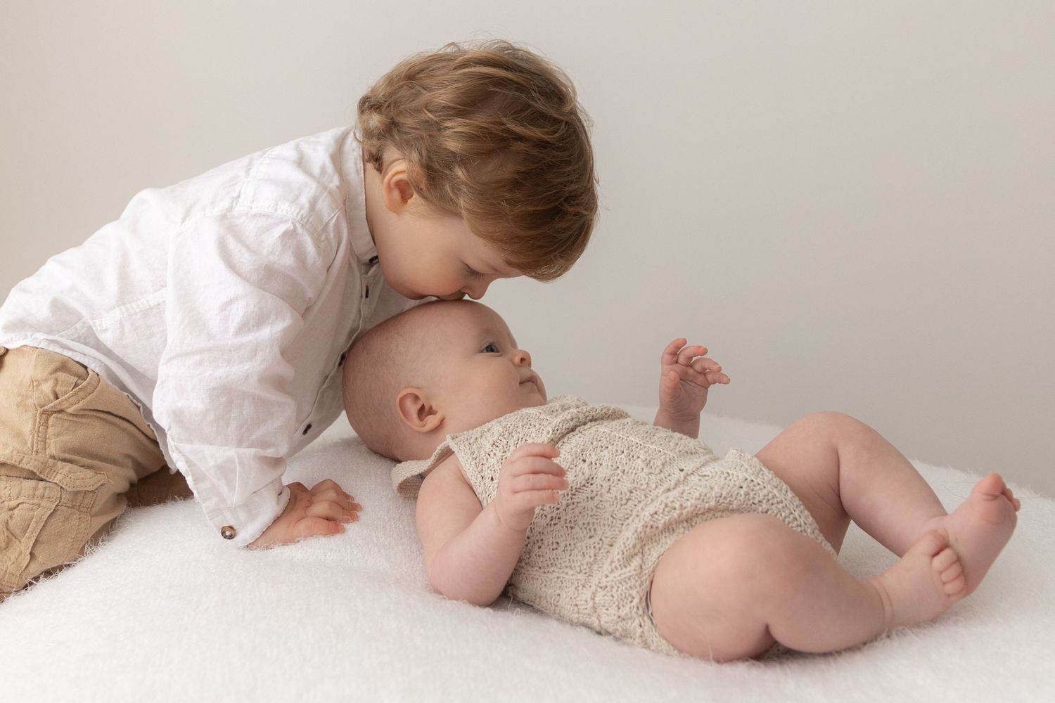 Sweet tender moment between two young siblings on white background.