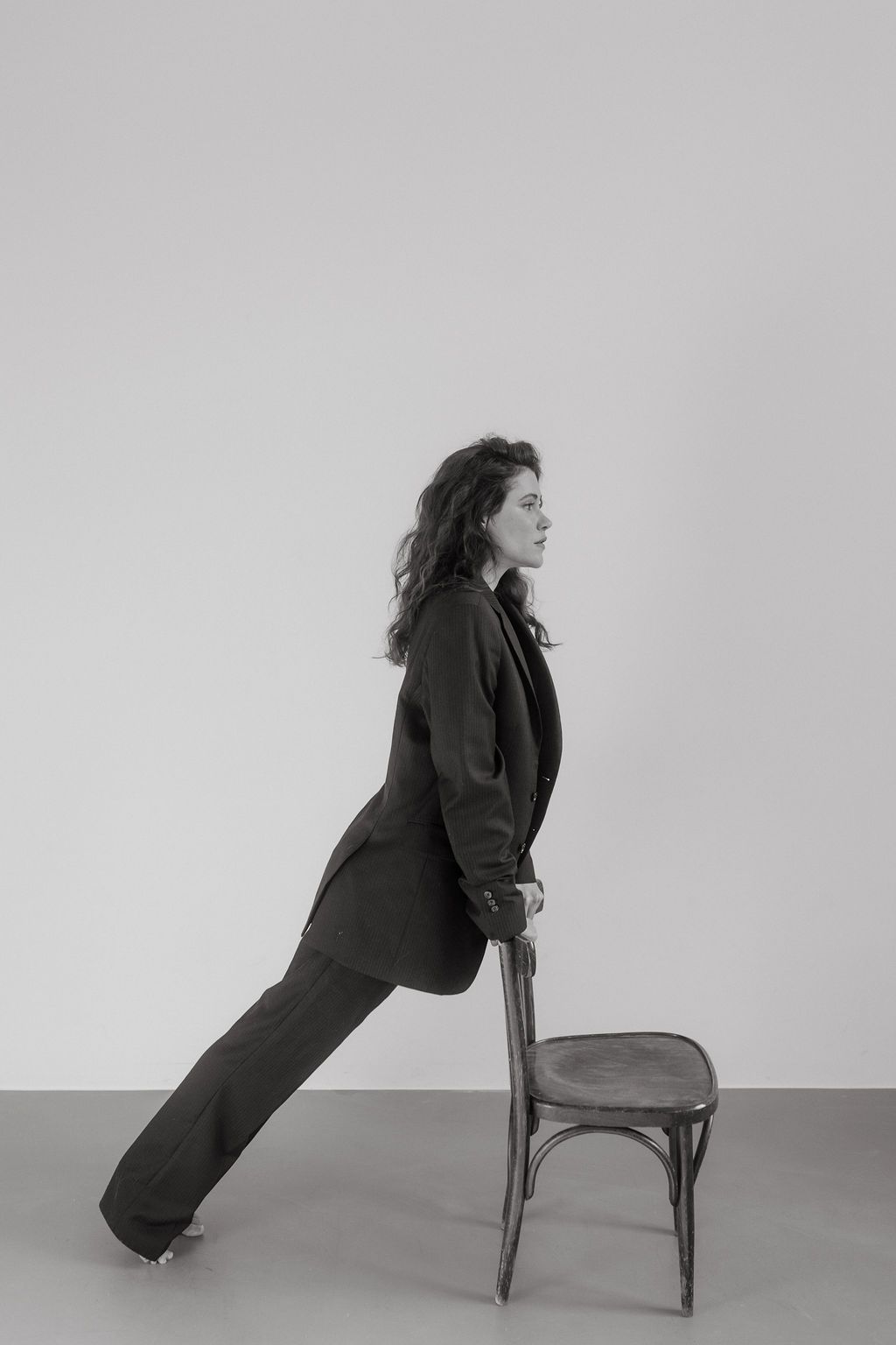 Dynamic black and white photos showing interaction with wooden chair against gray backdrop.