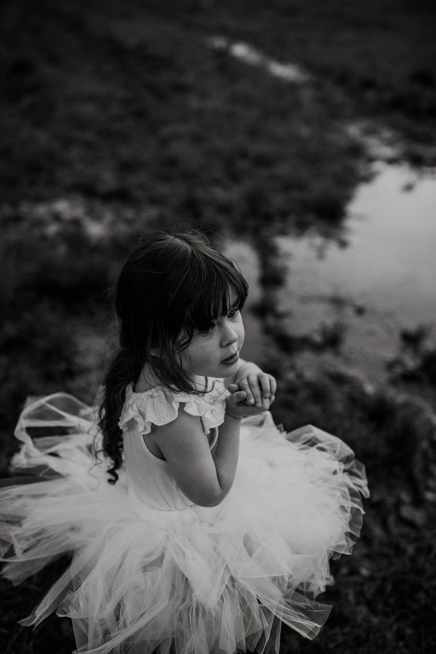Black and white portrait of child in tulle dress gazing thoughtfully.