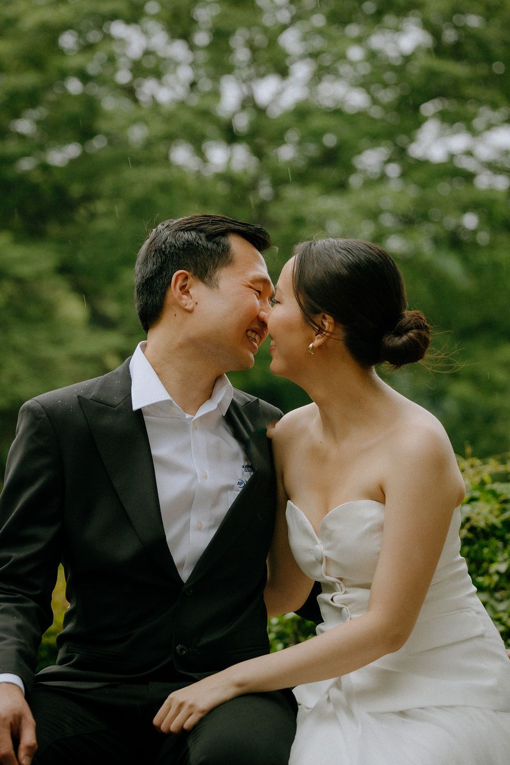 An intimate moment shared between a couple in formal attire against a green garden backdrop.