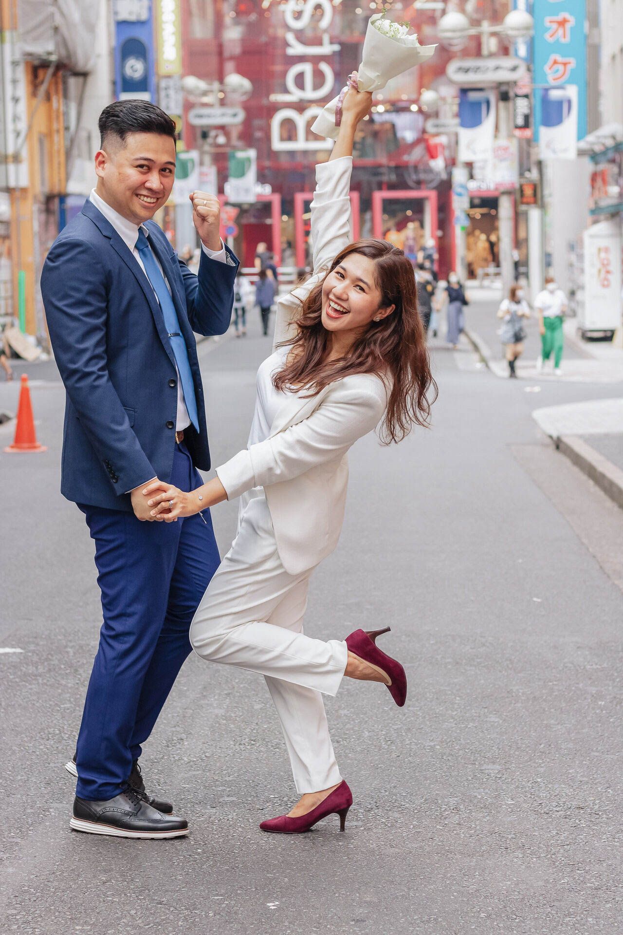 Joyful couple in formal wear having fun posing on a city street.