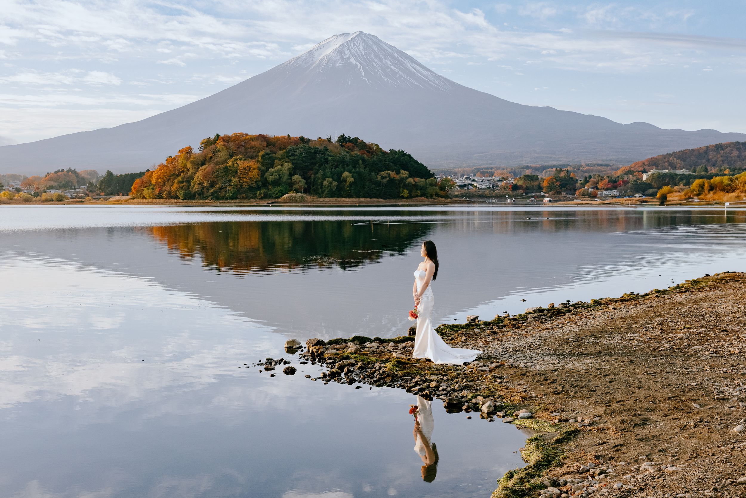A tranquil scene at Lake Kawaguchiko with Mount Fuji rising majestically in the background on a calm autumn morning.