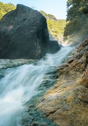 Rushing waterfall cascading over rocky cliffs in a natural setting.