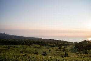 Panoramic view of coastal hills and ocean during sunset with soft lighting.