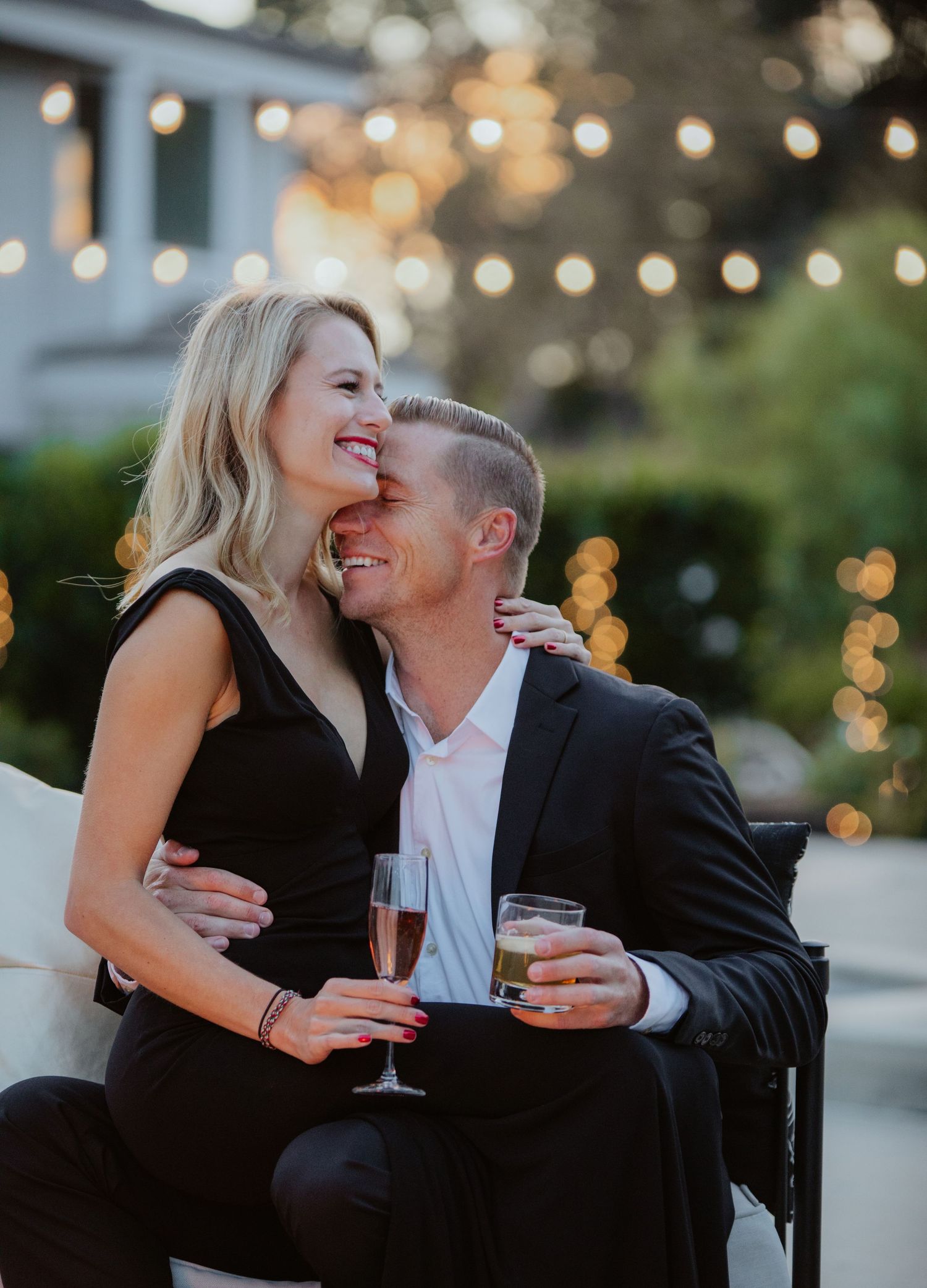 Romantic couple in all black attire, cuddling and celebrating with champagne.