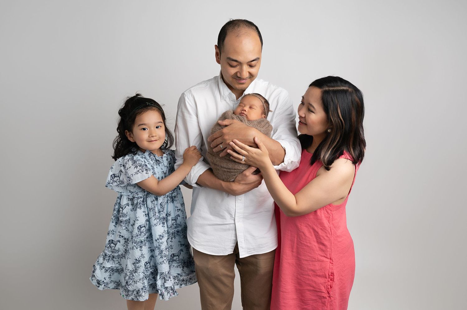 Happy family of four posing together against white studio background.