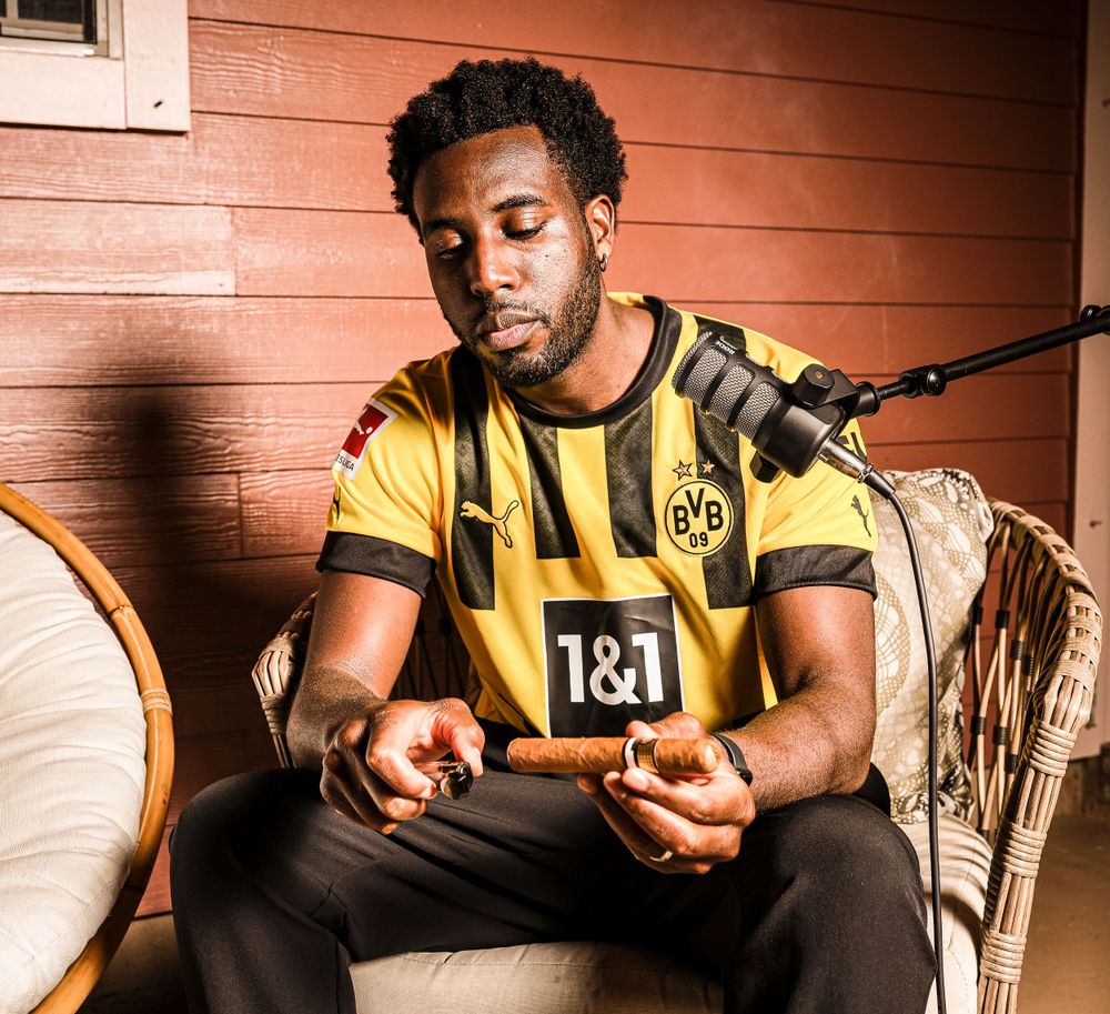 Person wearing yellow and black striped sports jersey relaxing on wooden porch.