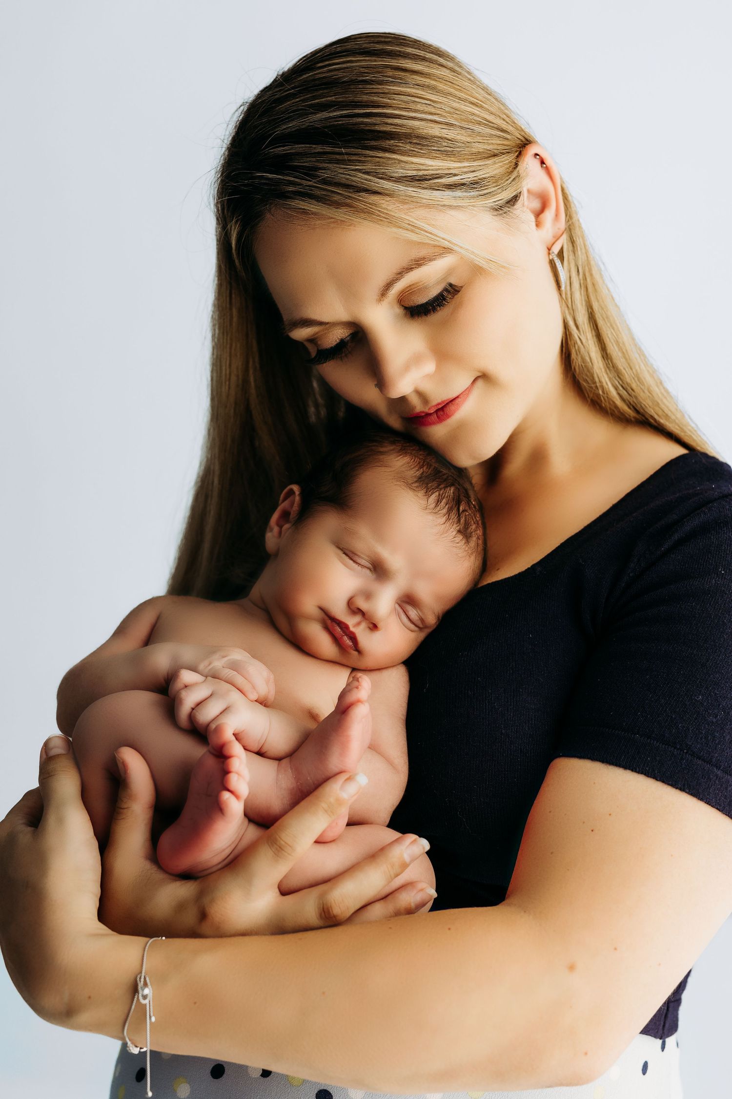A tender moment shows a woman in a black shirt cradling a sleeping newborn baby against her chest.
Rashinphotography-Nova photographer- DMV