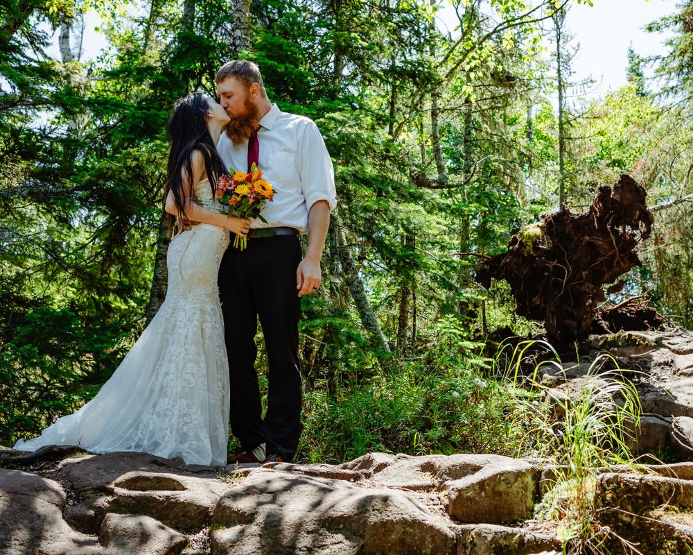 Wedding couple sharing intimate moment in lush green forest setting.