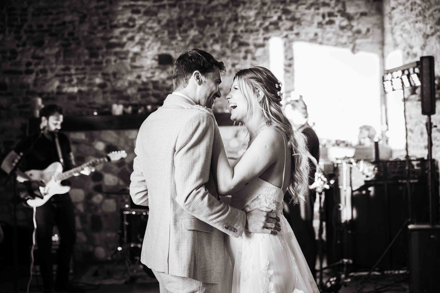 A romantic black and white wedding dance with a live band performing in the background at a rustic venue.