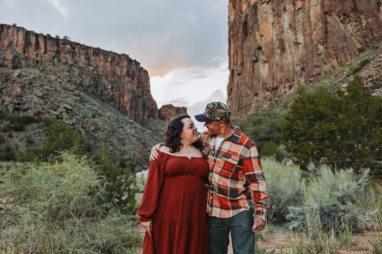 A romantic wedding couple sharing a tender moment against a rustic brown wall.