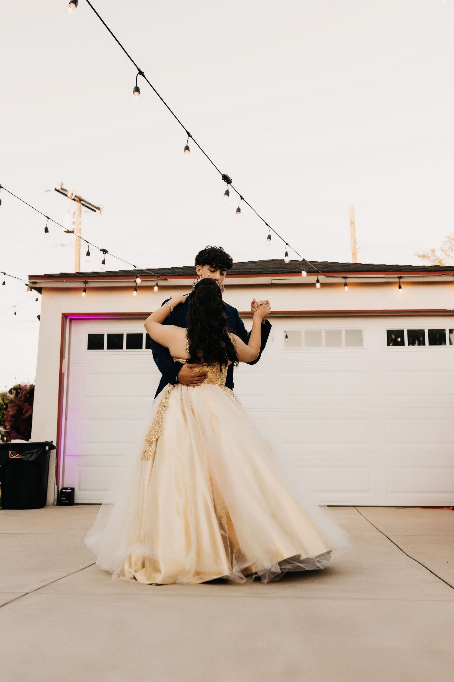 A romantic dance scene under string lights with a flowing cream-colored gown.