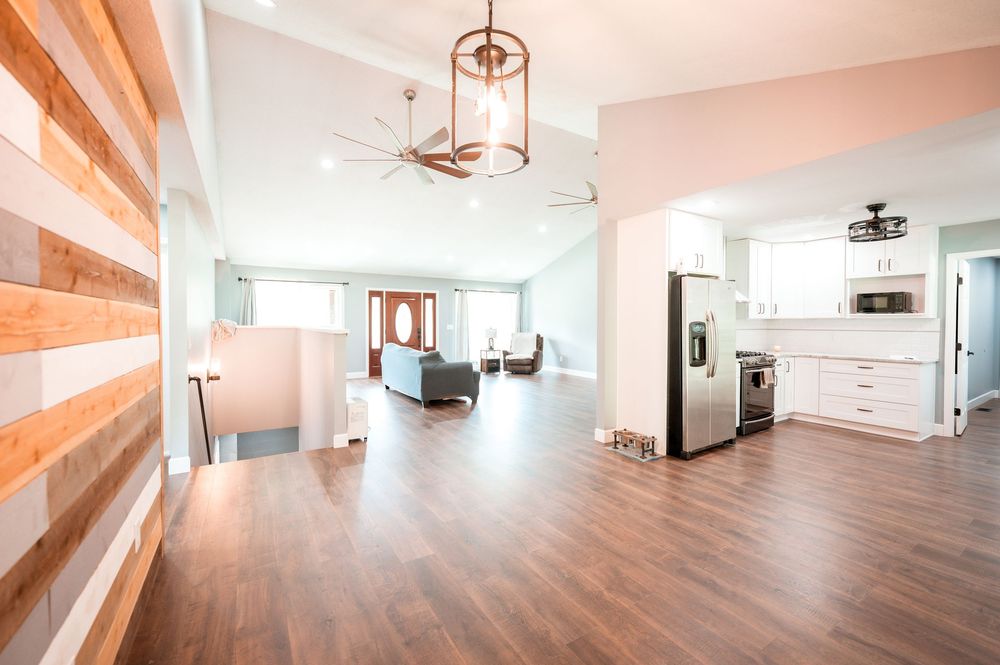 Modern open concept living space with hardwood floors, white walls, and pendant lighting showcases minimalist design.