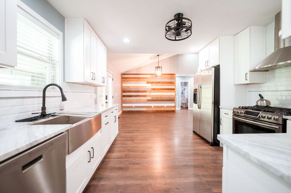Modern white kitchen interior with hardwood floors and sleek minimalist design.