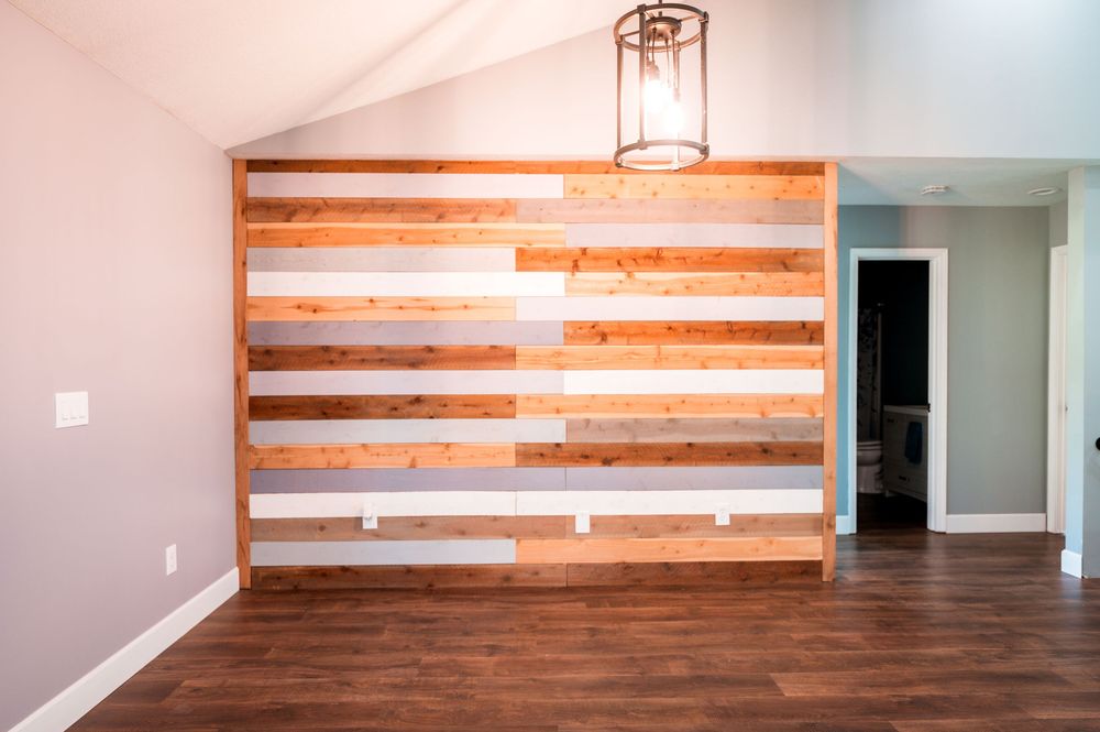Modern interior room with wooden accent wall featuring horizontal planks and contemporary ceiling light fixtures.