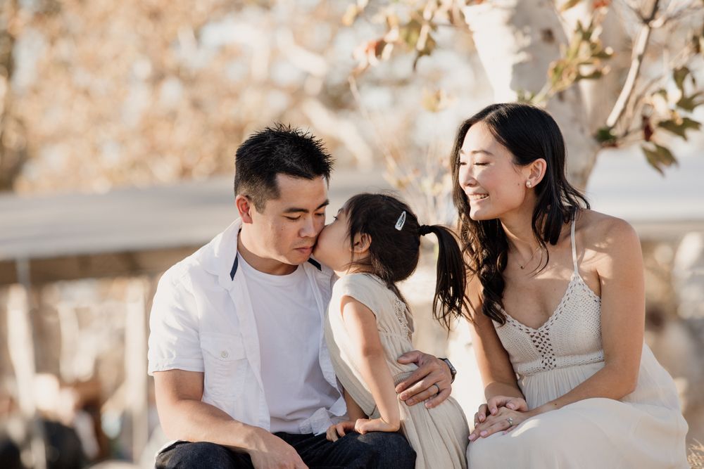 A tender family moment captured at an autumn pumpkin patch with warm lighting.