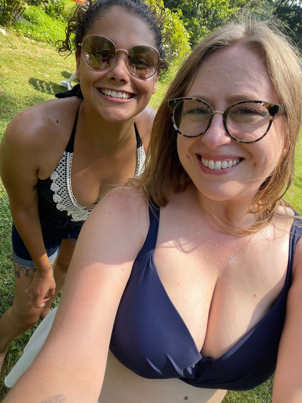 Two friends take a sunny outdoor selfie while enjoying a summer day.