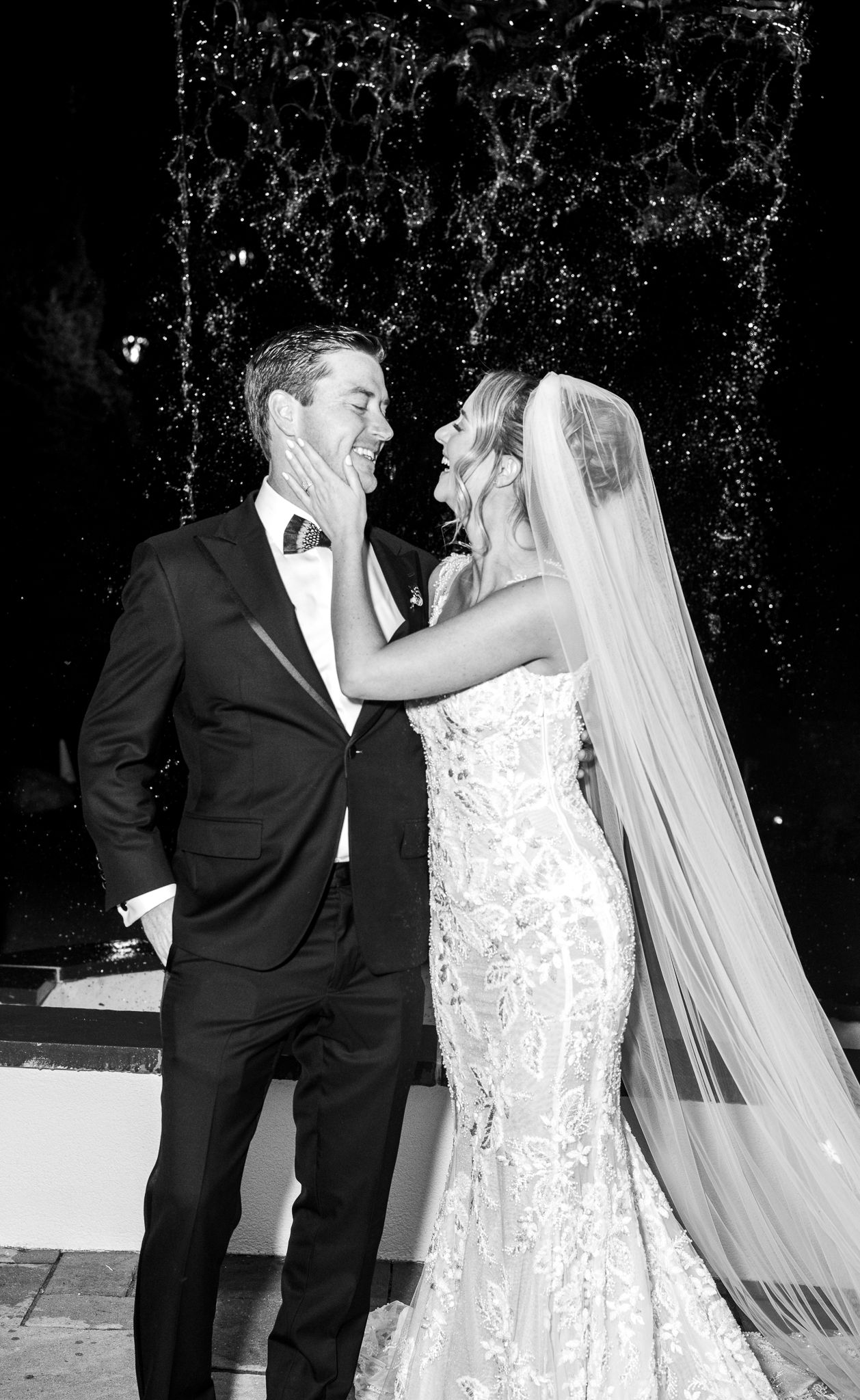 Romantic black and white portrait of newlyweds sharing intimate moment by fountain.