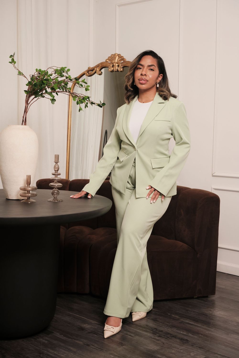 Model showcases oversized mint green blazer while posing in modern interior setting.