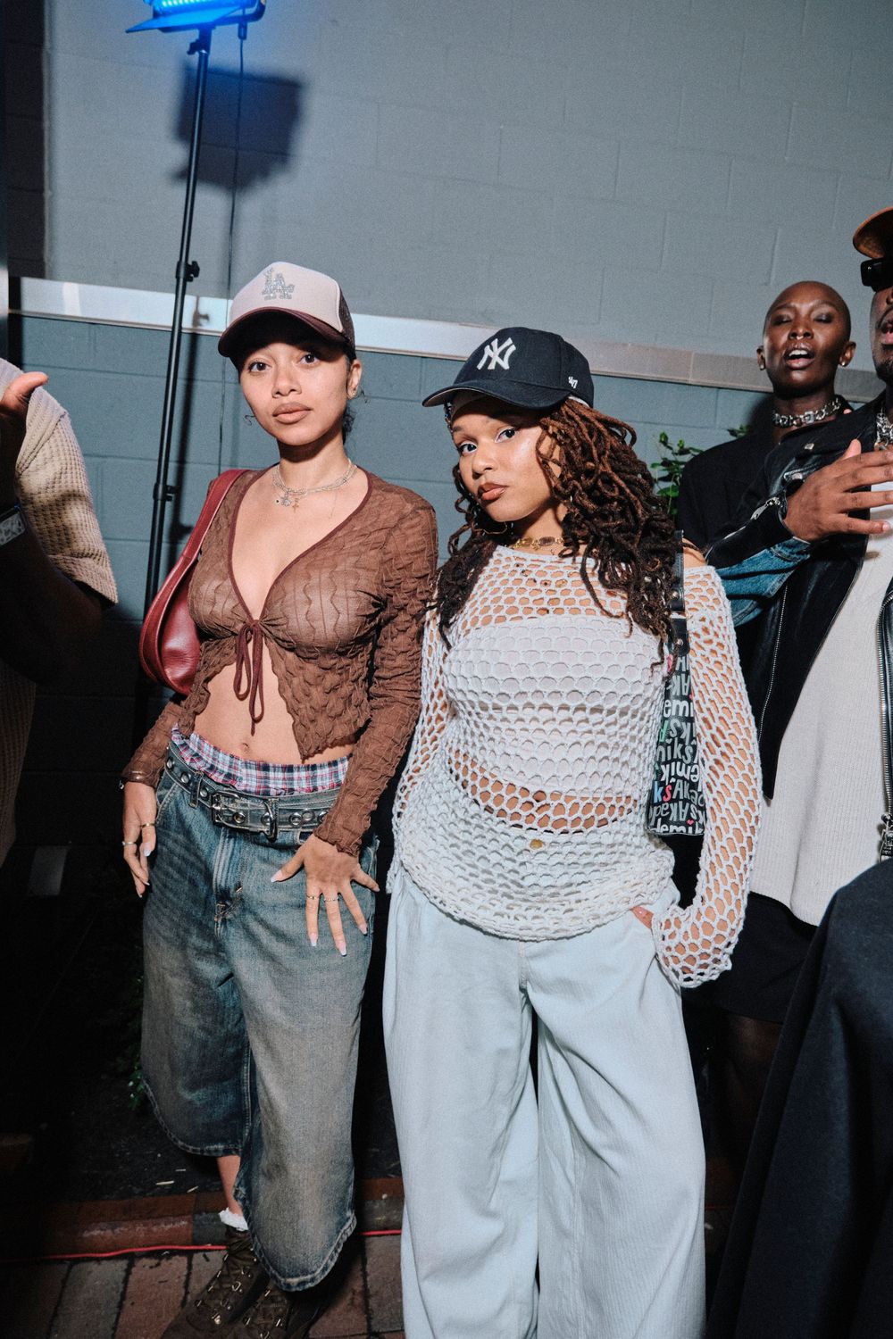 Group photo showing fashion models wearing mesh tops and casual streetwear at an event.