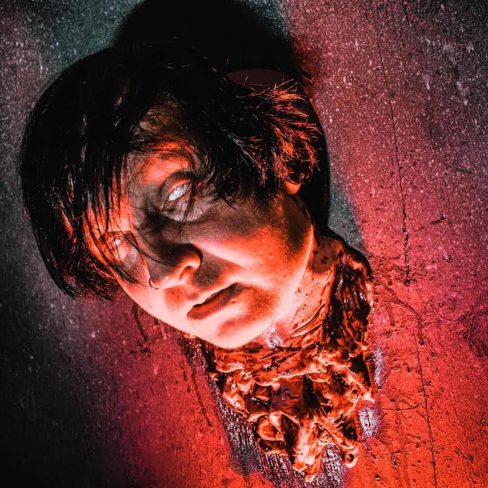 Artistic portrait with dramatic red lighting and wet effect creating moody atmosphere.