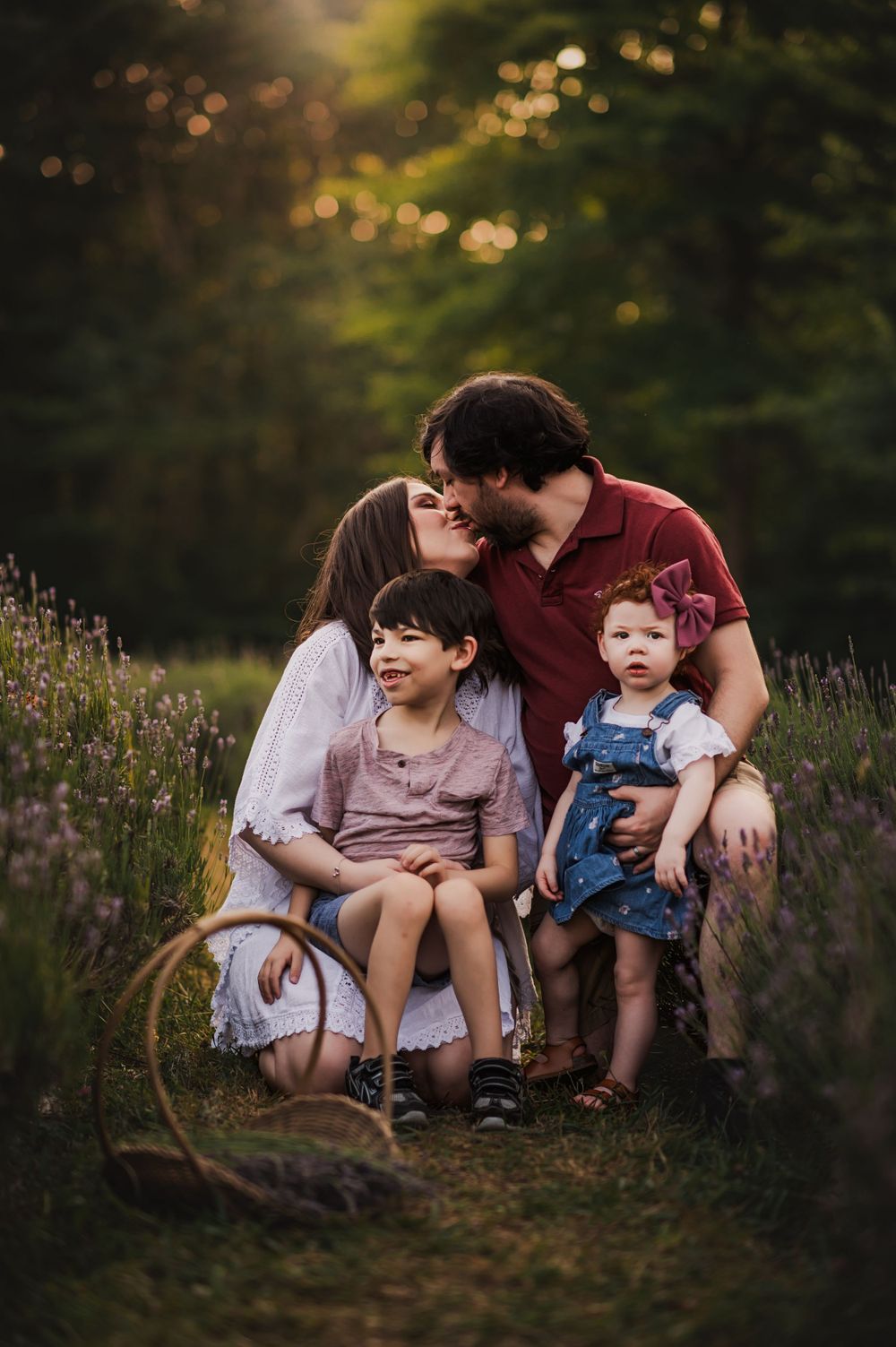 mom and dad crouch with 2 children and kiss in a row of lavender bushes for lavender field mini session