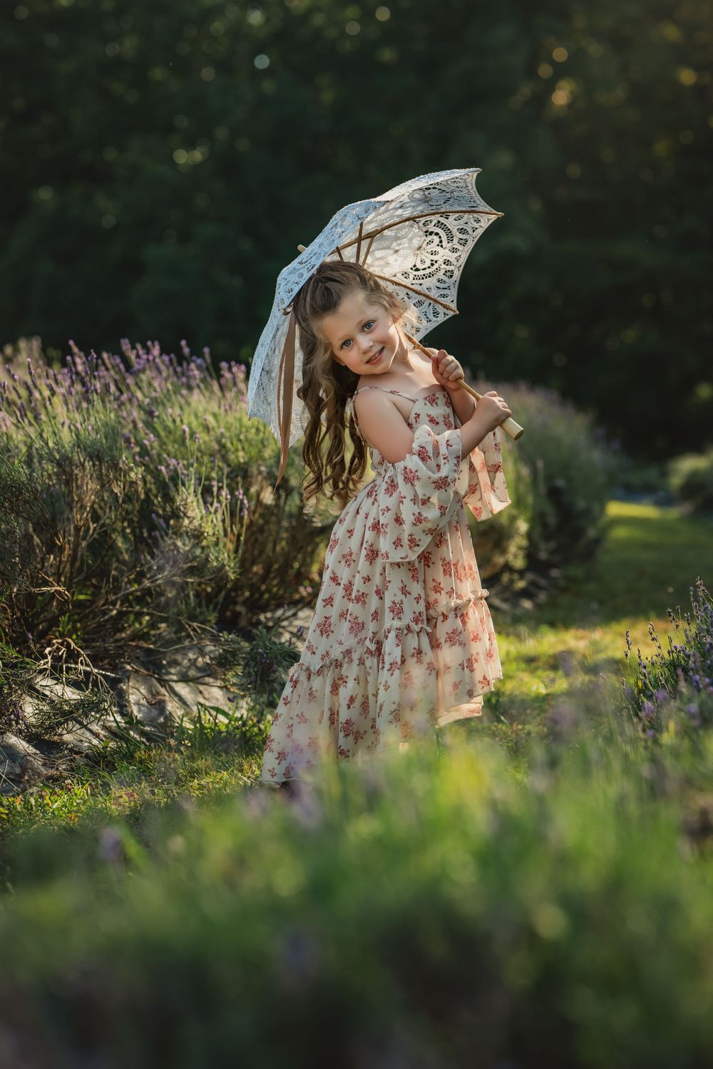 little girl in Joyfolie dress holds white lace parasol and spins in row of lavender bushes