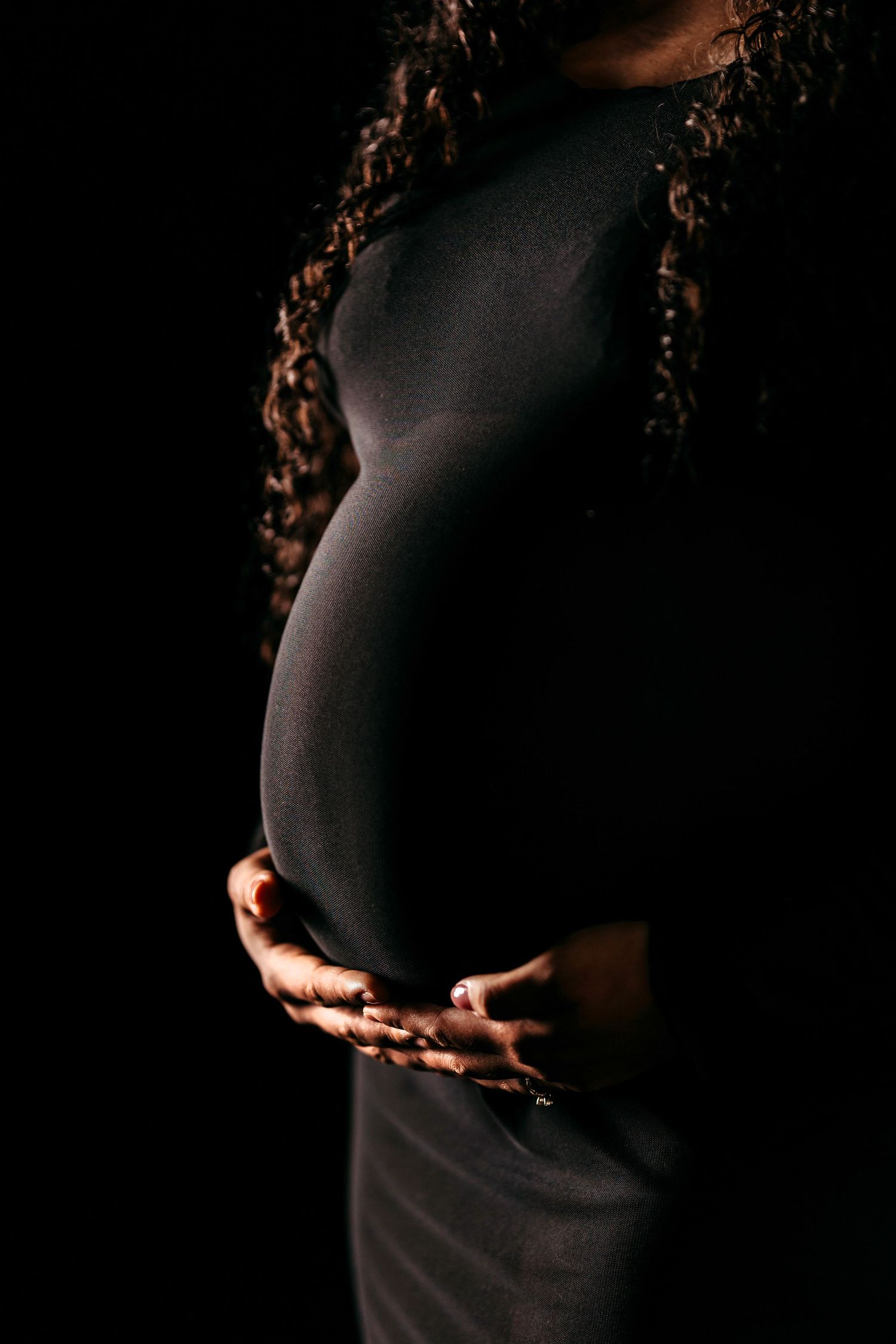 A series of dark silhouetted images showing a pregnant belly being cradled by hands in dramatic lighting. Middle Tennessee Luxury Maternity
