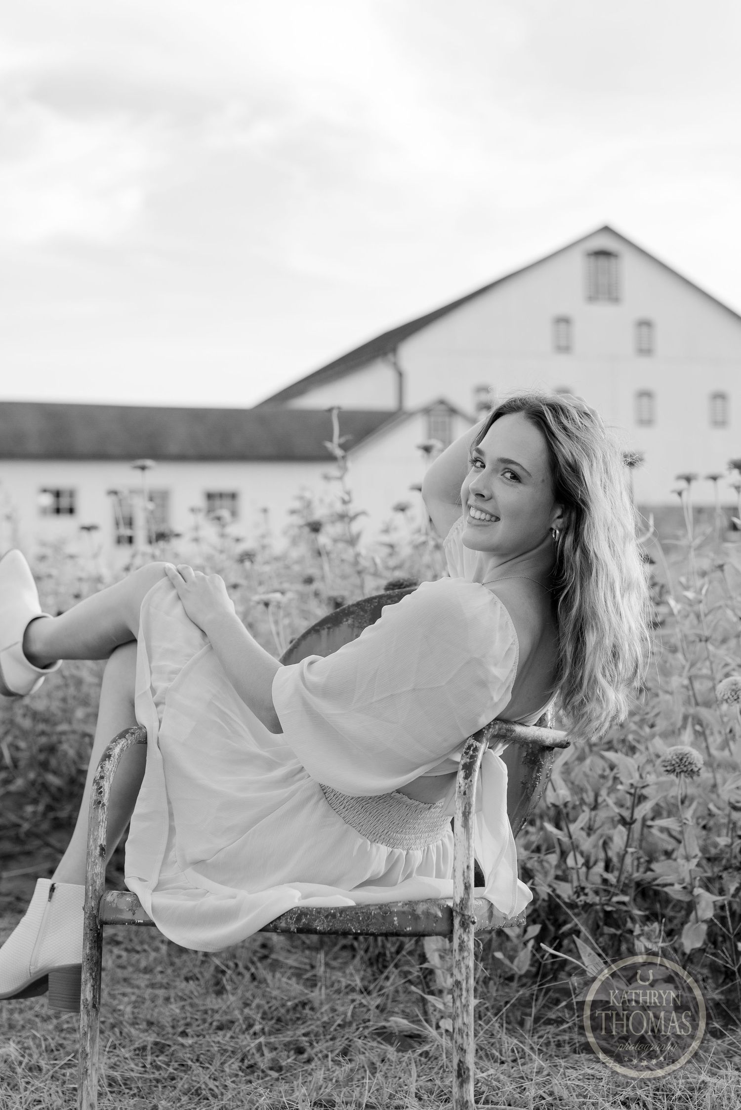A black and white portrait shows someone relaxing in a vintage chair among flowers.