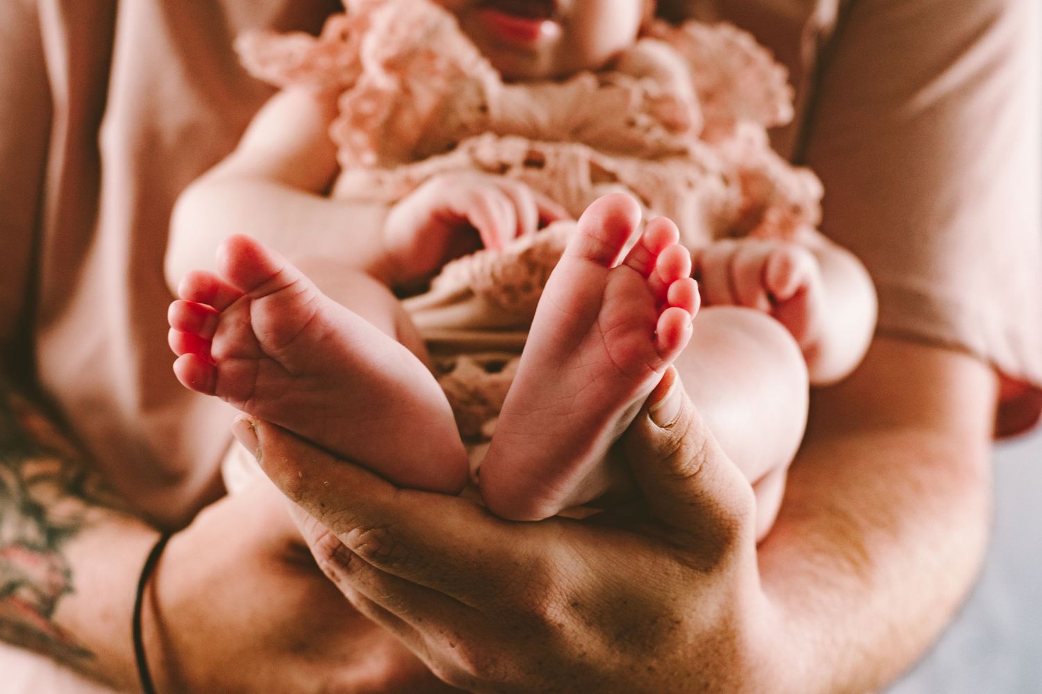 Close up of tiny baby feet being gently held in adult hands.