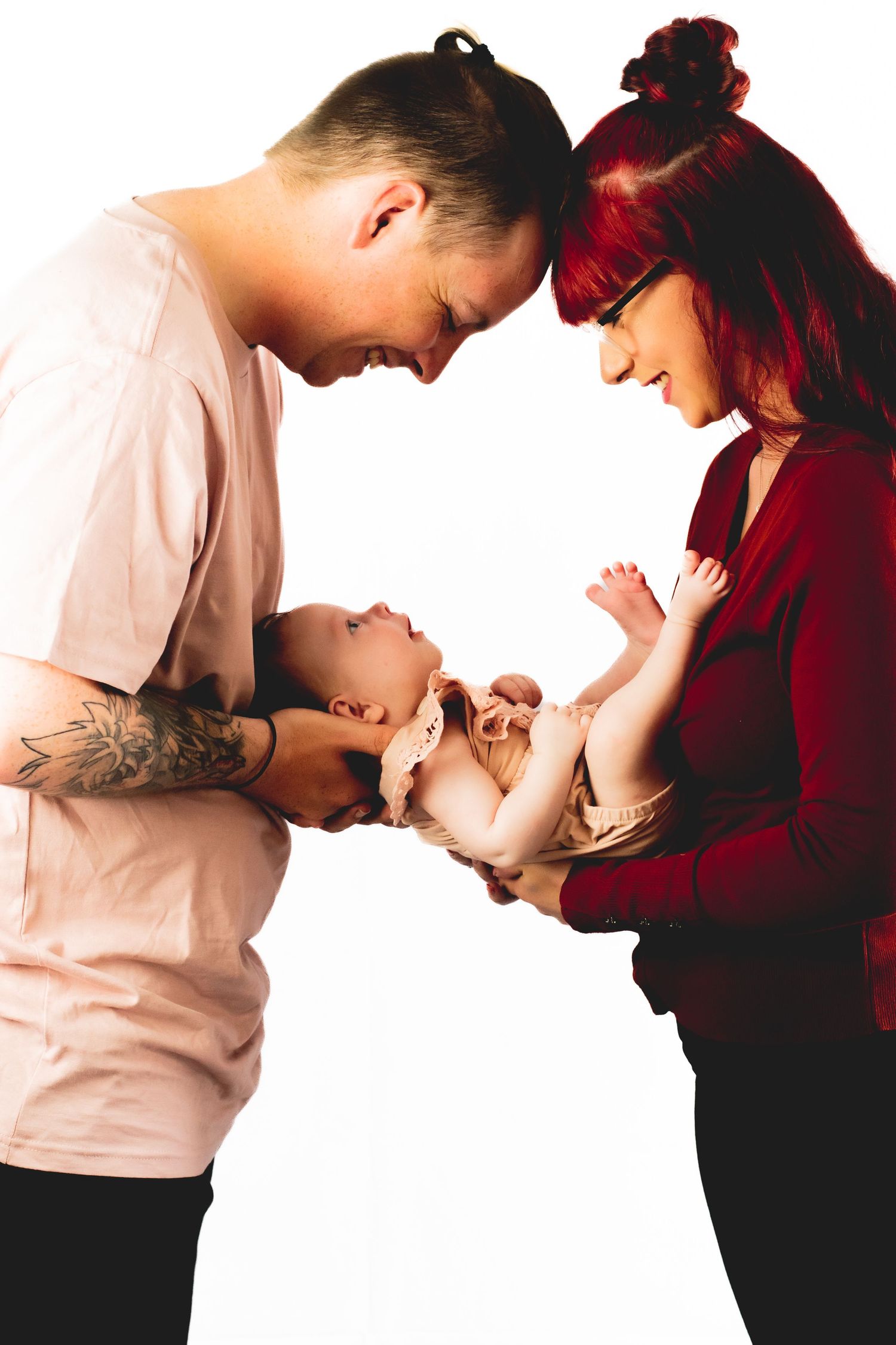 Parents lean in together to admire their baby in an intimate portrait.