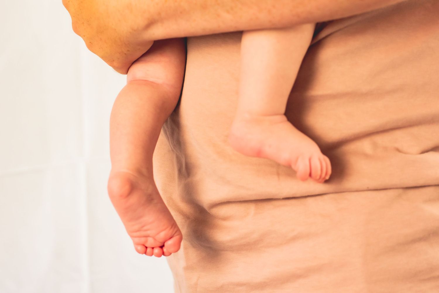 Close up of tiny baby feet against soft peach colored fabric.